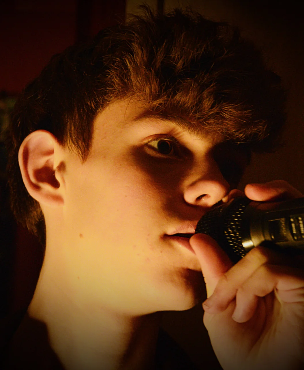 Samuel Thaon chante dans une lumière chaude, micro à la main.